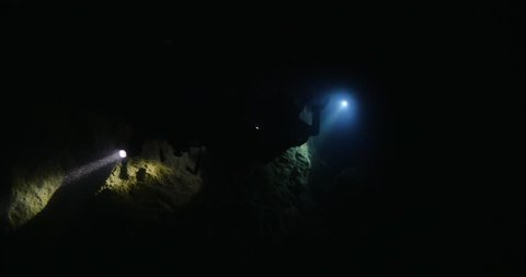 cave diving underwater scuba divers exploring cave dive with torch light in cavern ocean scenery
