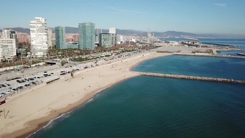 Aerial view of the beautifull beaches of Barcelona, Spain, in winter. Drone flies over the beaches Llevant and Mar Bella facing the modern district Diagonal Mar with its skyscrapers