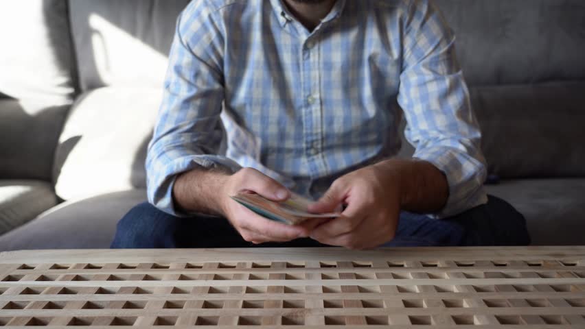 Video of a young man counting euro bills on the couch at home. Valuing his savings. Lifestyle. | Shutterstock HD Video #1014073913