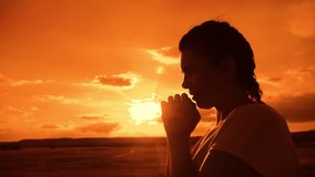 the girl prays. Girl folded her hands in prayer silhouette at sunset. slow motion video lifestyle. Girl folded her hands in prayer pray to God. girl praying asks forgiveness for sins of repentance