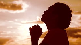 the girl prays. Girl folded her hands in lifestyle prayer silhouette at sunset. slow motion video. Girl folded her hands in prayer pray to God. girl praying asks forgiveness for sins of repentance