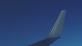 Plane is flying against of a clean blue sky background. View white wing through an airplane window. Hand shot filmed in 4k UHD 2160p (Part 2)