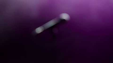 Close-up of the face of the singer with microphone on a black smoky background. The singer sings a song on stage in the dark, smoke, purple light, concert. : vidéo de stock