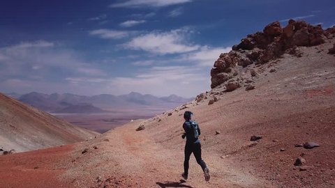 Male athlete running on the high mountain trail of the rocky desert in the Atacama desert. Aerial view, 4k
