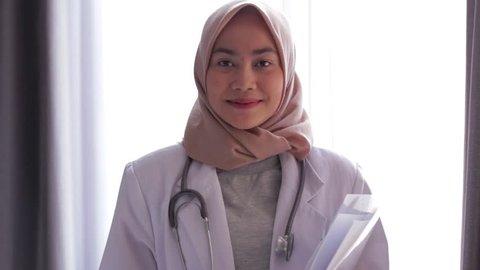 Portrait of asian female muslim doctor standing and smiling at camera at hospital. Edited and raw.