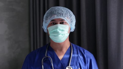 Young asian male doctor putting on surgical hat at hospital. Edited and raw.
