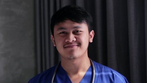 Close up portrait of asian male doctor smiling at camera in hospital. Edited and raw.