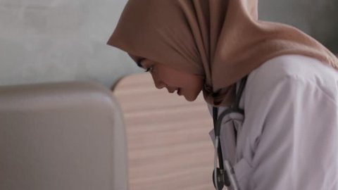 Young asian muslim female doctor making injection to the patient. Edited and raw.