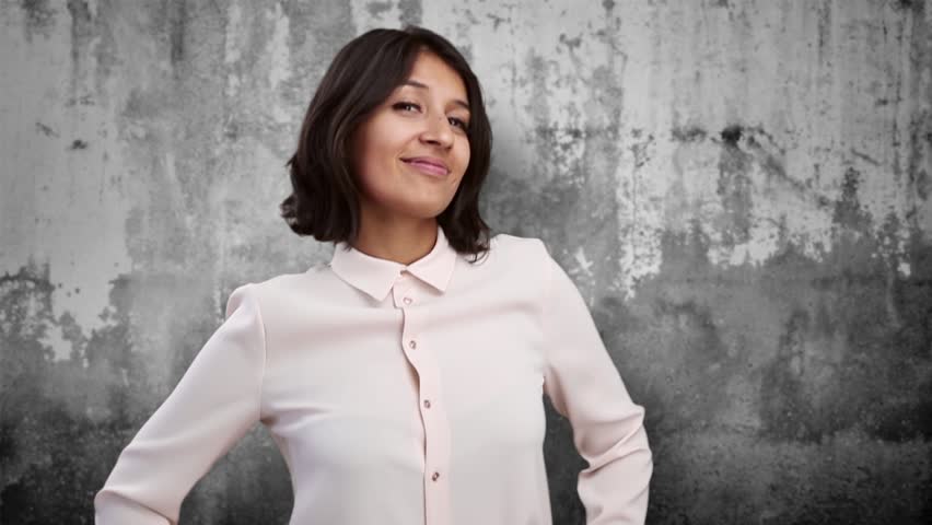 Young indian woman gesturing and having fun with a wall as a background.