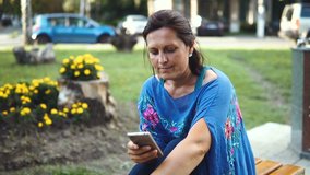 Portrait of Amazing Woman with Smartphone Outdoors. Pretty Brunette Using Her Mobile Phone with Touch Screen Standing in the Park