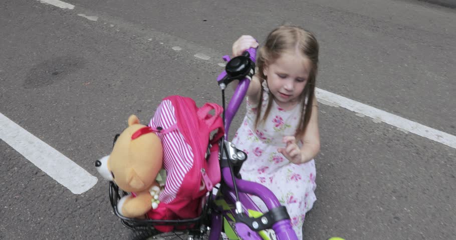 In the park the little girl is examining a bicycle