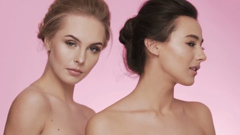 Cute girls posing at pink background posing, looking at camera, beauty video concept, skin care