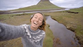 Young woman talking selfie video during a vacation travel holiday adventure in Iceland, Tourist woman enjoying her vacation in Iceland by famous Kirkjufell mountain. Travel and lifestyle concept