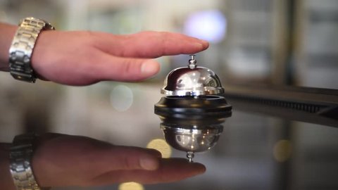 Bell on reception at the hotel to call the administrator. Beautiful blurred background. The hand of the man who presses the call. Close up. Cool concept for hotels. Filmed in July 2018.