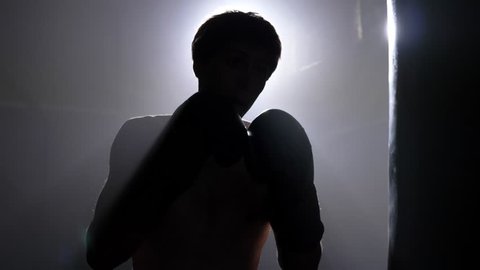 Kickboxer shadow boxing punching bag, training for championnat, smoke and brick illumination