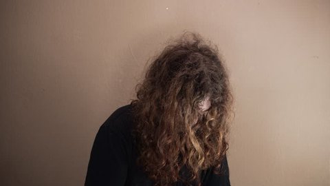 Long haired Caucasian man looking into camera dishevelled and depressed