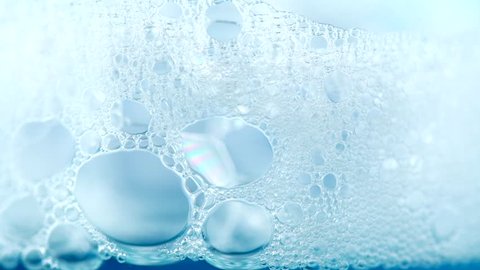 Foam. Soap foam popping bubbles background. Soap sud macro structure. Blue backdrop. 4K UHD video