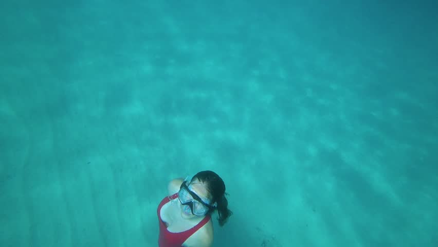 Young woman swims up to the surface of a blue clear sea. Slow motion 120 FPS