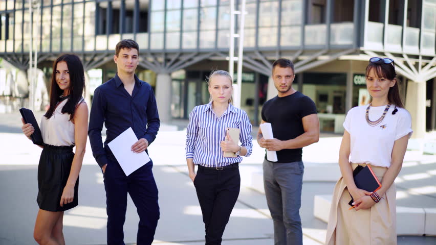 Portrait of young diverse business team near office. A group of business people stand together with serious look. Royalty-Free Stock Footage #1014118136