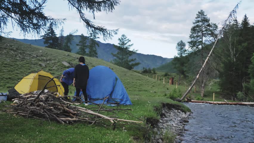 Young couple breaks camp in the high mountains and puts up the tent