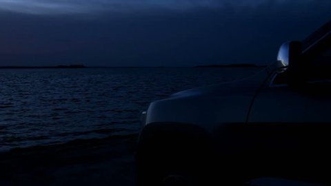 Silhouette of a SUV car at the beach with oceanview at twilight