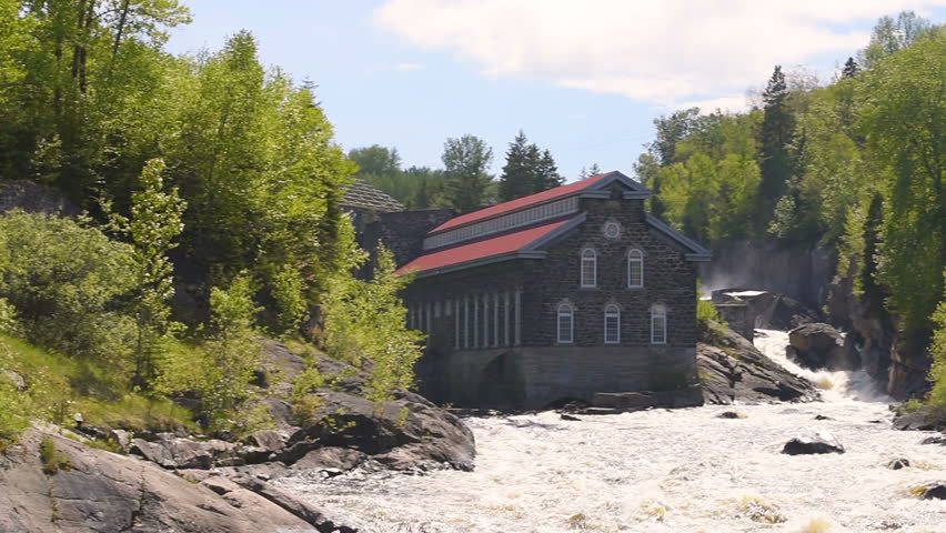 Panning of La Pulperie de Chicoutimi Regional Museum Pulp mill in Saguenay, Quebec, Canada with river and water current flowing in summer
