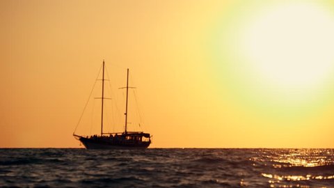 Sailing yacht in the open sea at sunset, rocking on the waves
