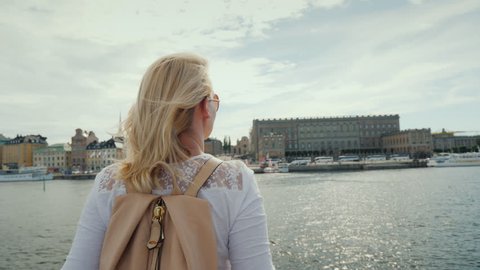 A woman with a pink backpack admires a beautiful view of the city of Stockholm in Sweden. Journey through the Euprope concept