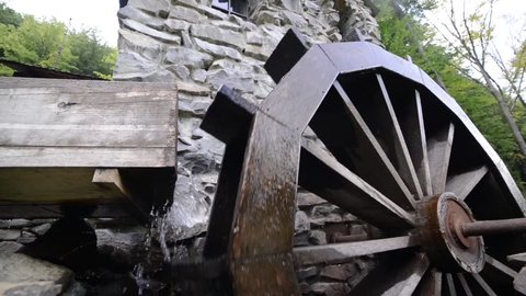 Old waterwheel mill. Water wheel. Water falls on an old water wheel. The old wooden mill wheel