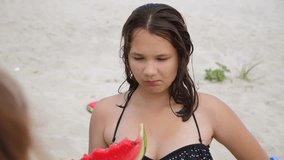 Child eating watermelon in on the beach slow motion video. girl teenager with pimples eating watermelon. concept girl lifestyle and watermelon