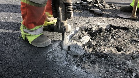 Hackhammer machine destroying asphalt road