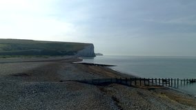 Drone rises over the beach at Cuckmere Haven with the famous Seven Sisters cliffs behind. Sussex, England
