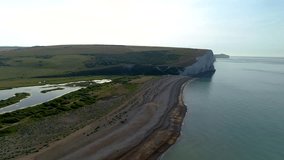 Drone flies over the beach at Cuckmere Haven to reveal the famous Seven Sisters cliffs behind. Sussex, England