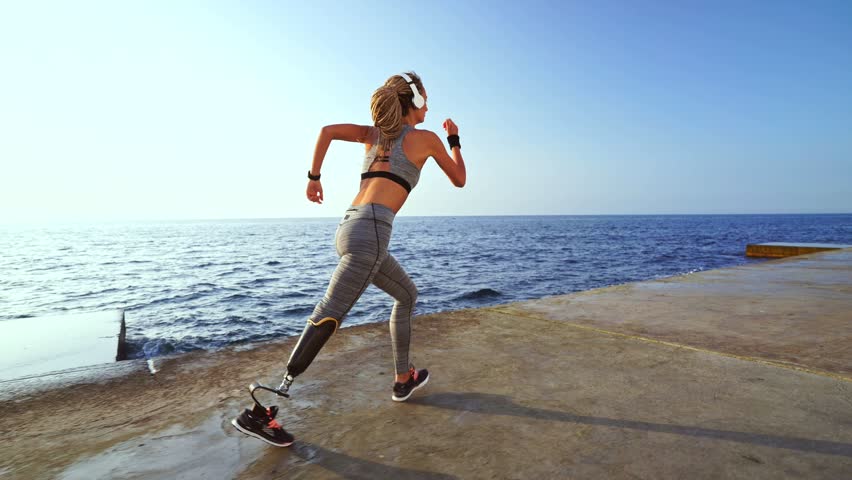 Side view of motivated disabled athlete woman with prosthetic leg running at the beach Royalty-Free Stock Footage #1014148169