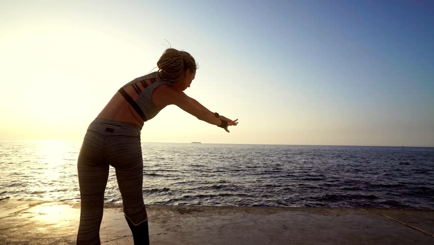 Back view of motivated disabled athlete woman with prosthetic leg warming up at the beach Royalty-Free Stock Footage #1014148181