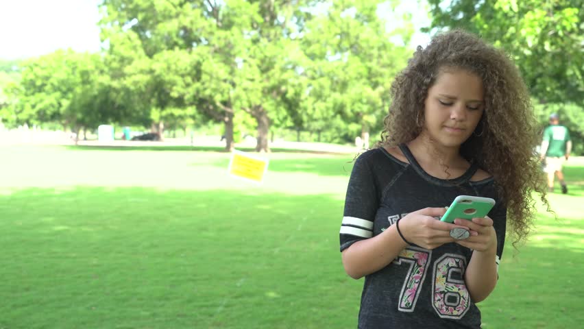 Young teenage girl responds to text on her phone with sad expression. 