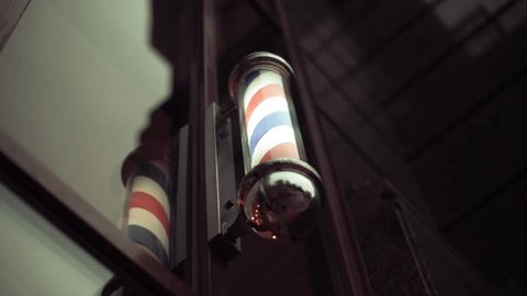 Barber pole spinning at night. International barbershop pole sign