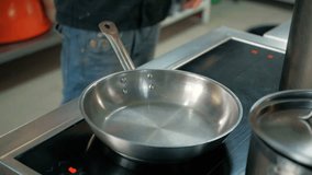 Pouring oil into frying pan in a restaurant kitchen.