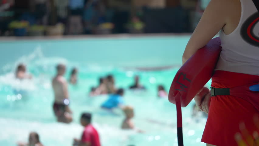 Close up shot of a lifeguard watching over kids and families playing in a wave pool Royalty-Free Stock Footage #1014175085