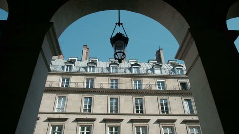 Tracking right view between colonnade arches of typical Parisian style building near Place Vendome in Paris, France