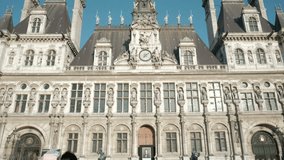 Camera dolly forward tilt up to centered clock and front facade of Hotel De Ville city hall in Paris, France