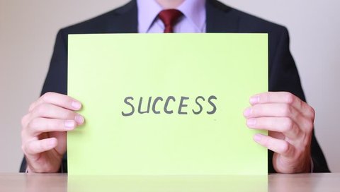 Holding sheet of paper with "Success" inscription