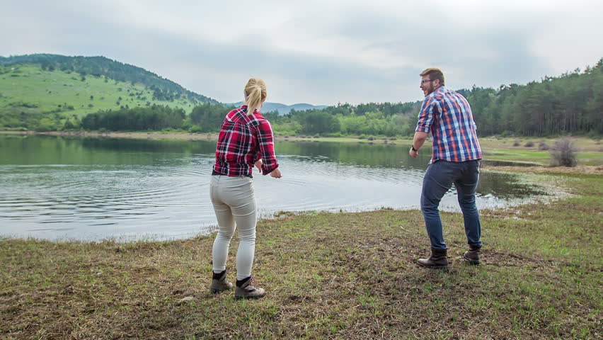 Two friends are throwing stones into the water. They
