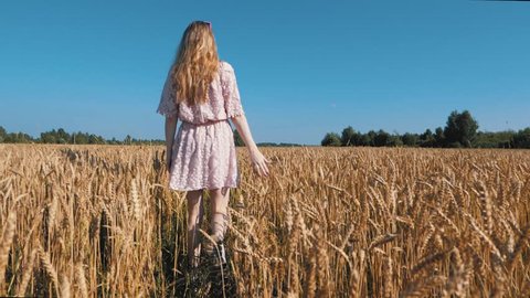Girl walking on the field with wheat