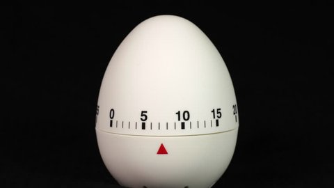 White kitchen egg timer countdown to zero time lapse on a black background.