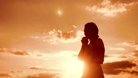 woman praying on her knees. Girl folded her hands in prayer lifestyle silhouette at sunset. slow motion video. Girl folded her hands in prayer pray to God. the girl praying asks forgiveness for sins