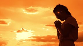 the girl prays. Girl folded her hands in prayer silhouette at sunset. slow motion video. Girl folded her hands in prayer pray to God. girl praying asks forgiveness lifestyle for sins of repentance