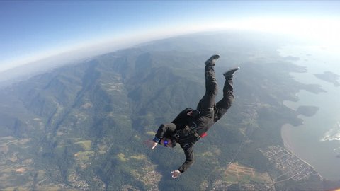 Skydiver having fun above the sea & mountains 4K: stockvideo