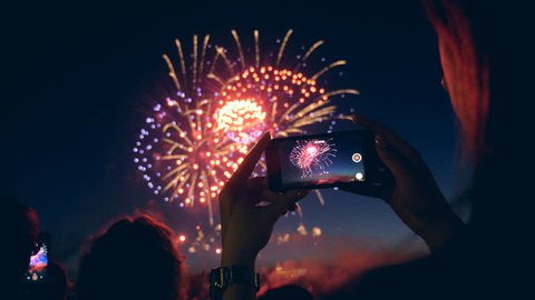 A woman captures fireworks on video, close up.