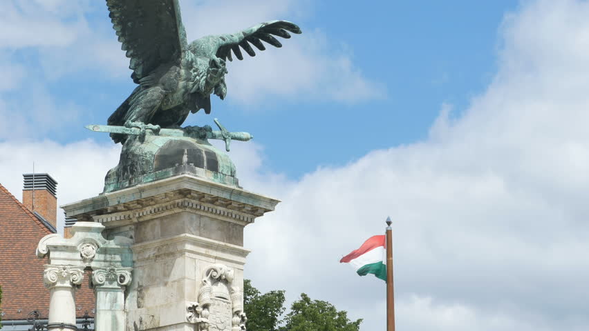 Hungarian flag waving in wind and bronze eagle statue at Buda Castle in Budapest.